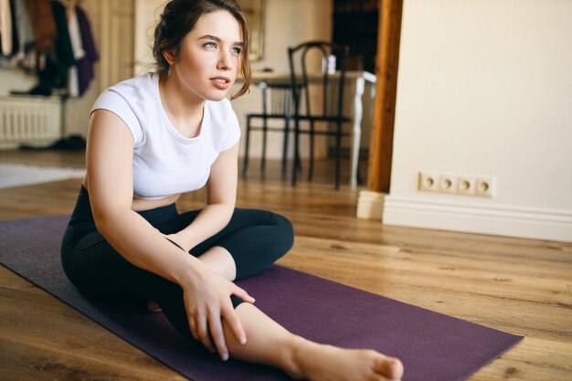 Gefrustreerde ongelukkige jonge vrouw met hamstringblessure tijdens het beoefenen van yoga zonder de juiste uitlijning en controle