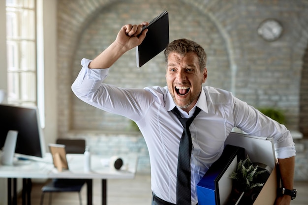 Gefrustreerde zakenman die schreeuwt terwijl hij zijn spullen gooit nadat hij van zijn werk is ontslagen