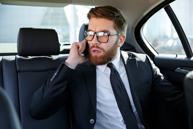 Gefrustreerde zakenman in brillen praten op mobiele telefoon
