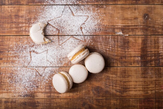 Gegeten maanvorm bitterkoekjes met stervorm op suikerpoeder over het houten oppervlak