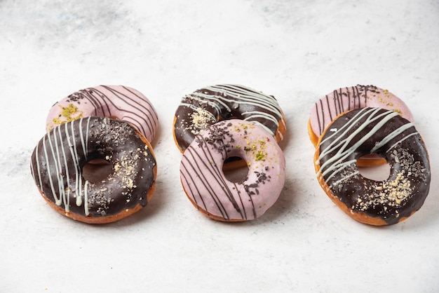 Geglazuurde chocolade en roze donuts op wit oppervlak.