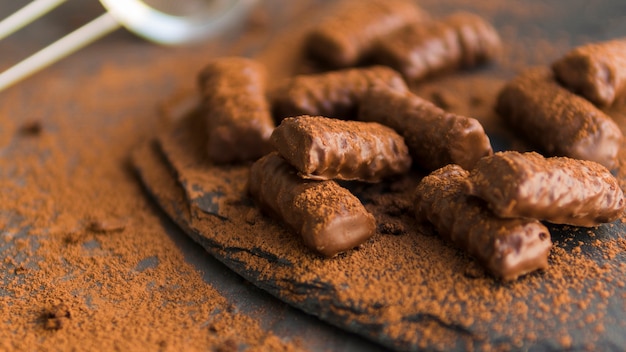 Gratis foto geglazuurde chocoladekoekjes bedekt met cacaopoeder op zwarte plaat