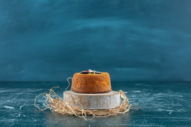 Geglazuurde minicake op een bord, op de blauwe tafel.