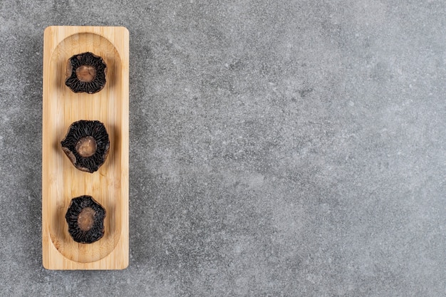 Gratis foto gegrilde champignons op een houten bord over grijze ondergrond