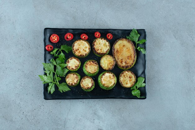 Gegrilde gesneden courgette op zwarte plaat.