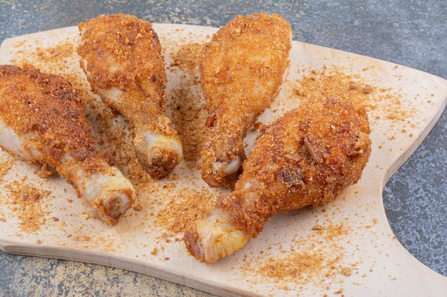 Gegrilde kip drumsticks op een houten bord met broodkruimels. Hoge kwaliteit foto