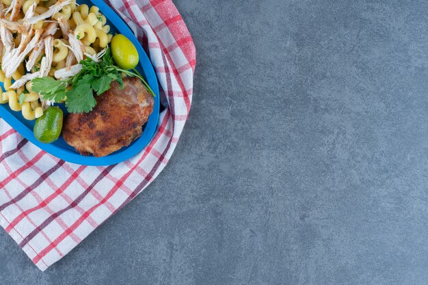 Gegrilde kip en pasta op blauw bord.