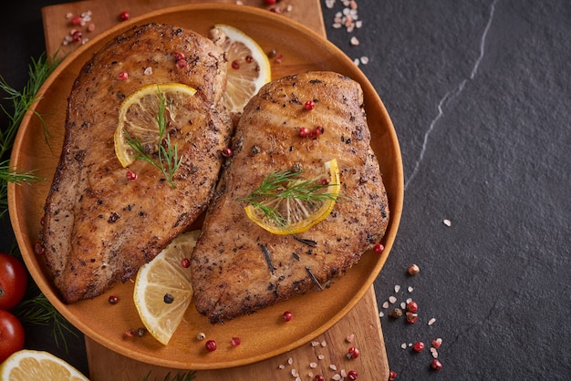 Gegrilde kipfilet op een houten bord en groenten met tomaten en champignons