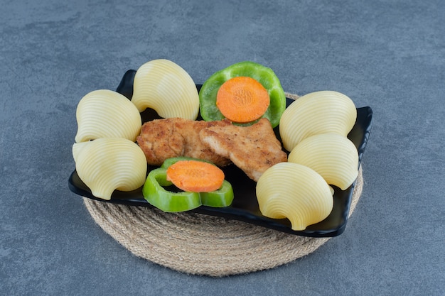 Gegrilde kipnuggets en gekookte aardappelen op zwarte plaat.