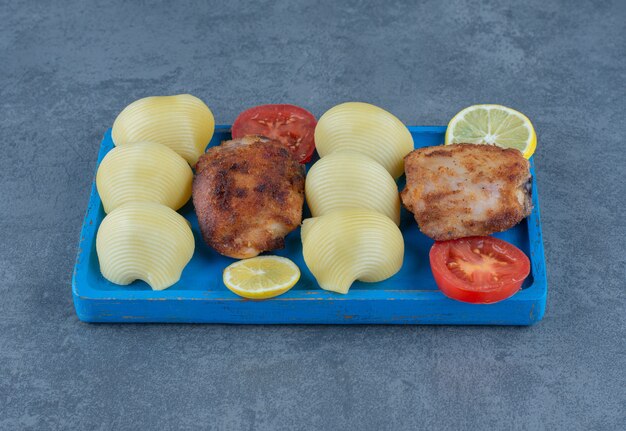 Gegrilde kippendelen en gekookte aardappelen op blauw bord.