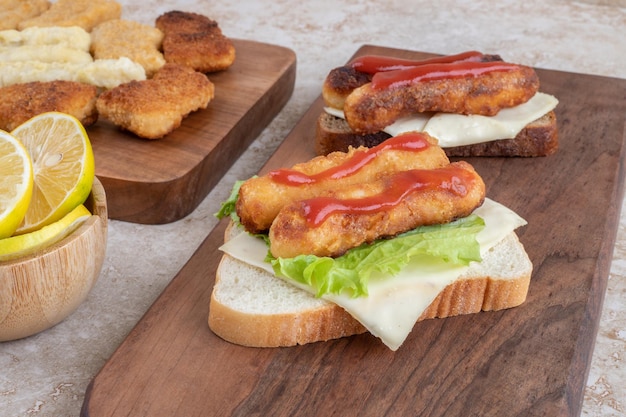 Gegrilde worst en kipnuggets op sandwich toastjes met kruiden en specerijen op een houten schotel.
