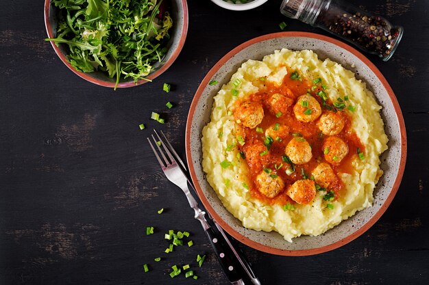 Gehaktballetjes in tomatensaus met aardappelpuree in kom.