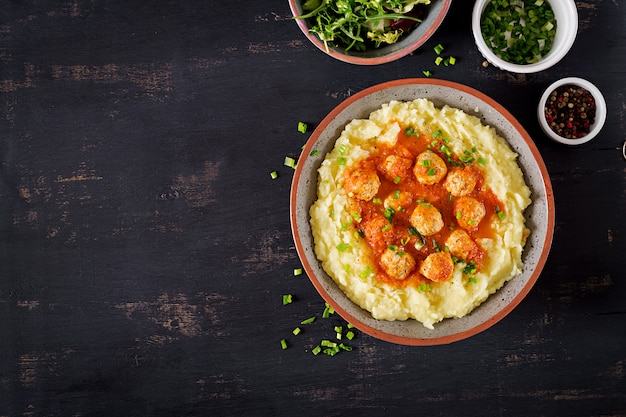 Gehaktballetjes in tomatensaus met aardappelpuree in kom.