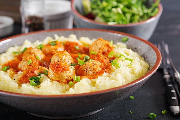 Gehaktballetjes in tomatensaus met aardappelpuree in kom.