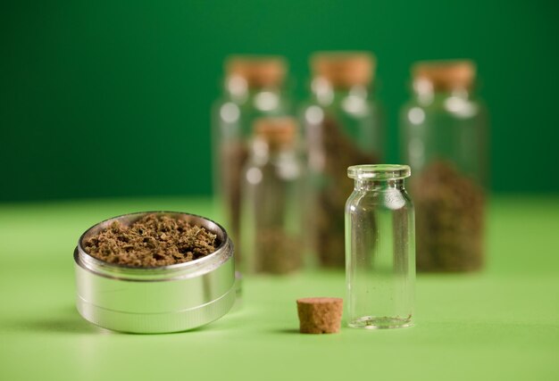 Gehakte marihuana in een grinder en luchtdichte glazen potten met verschillende soorten cannabis