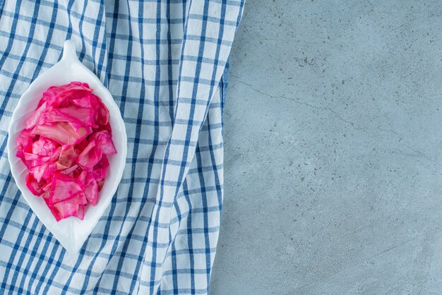 Gehakte rode gefermenteerde zuurkool in een kom op een onderzetter, op de blauwe tafel.