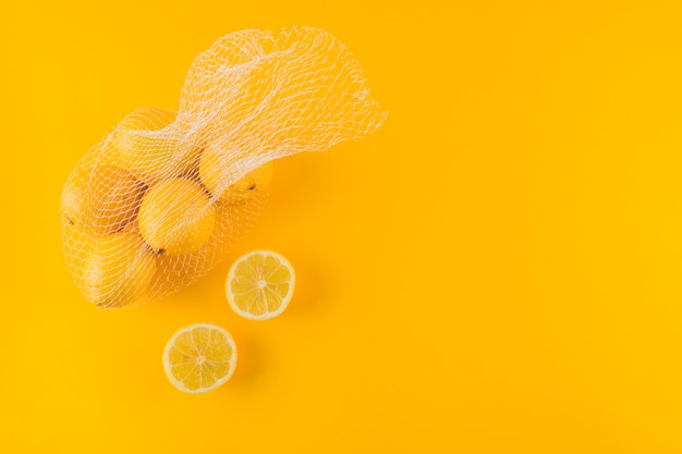 Gehalveerde en gehele rijpe sappige citroenen op gele achtergrond