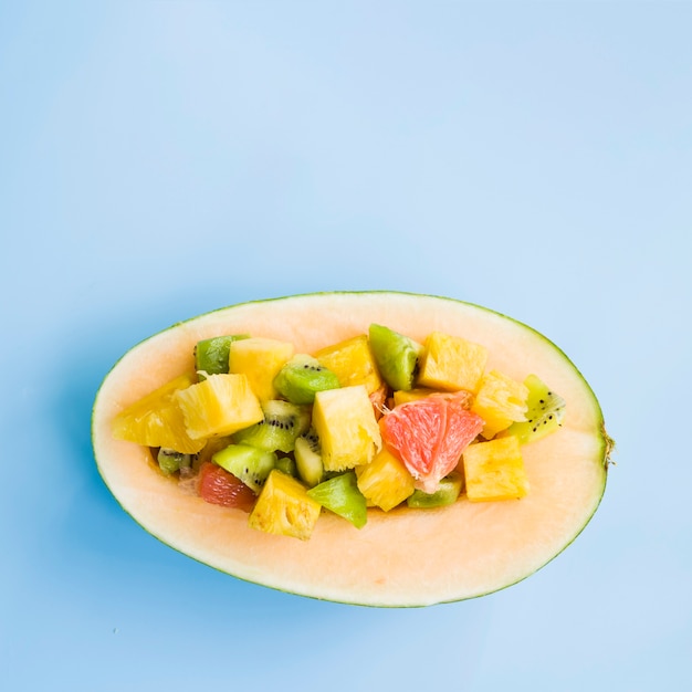 Gehalveerde meloen met plakjes fruit op blauwe achtergrond