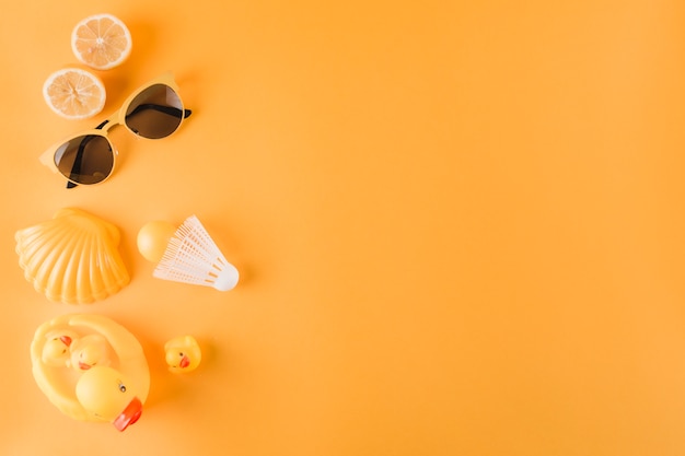 Gehalveerde sinaasappelen; zonnebril; plastic bal; shuttle; coquille en rubberen eend op gekleurde achtergrond