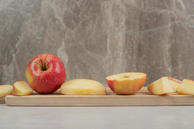 Geheel en plakjes rode appel op een houten bord