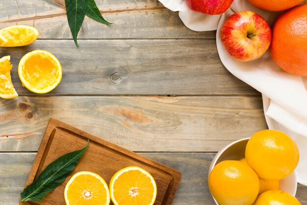 Geheel en plakjes sinaasappelen met appels op houten bureau