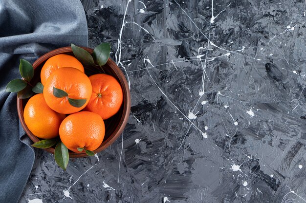 Geheel vers oranje fruit met bladeren in een bord.