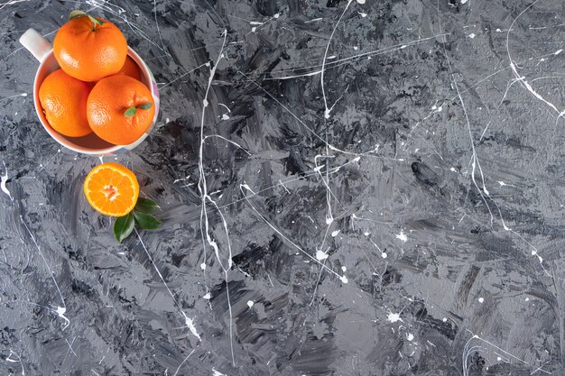 Geheel vers oranje fruit met bladeren in een witte kom.