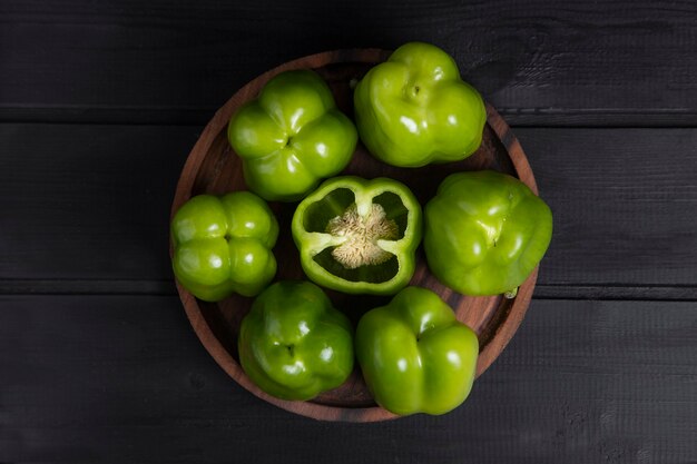 Gehele en gesneden groene paprika's die op houten donkere lijst worden geplaatst. Hoge kwaliteit foto