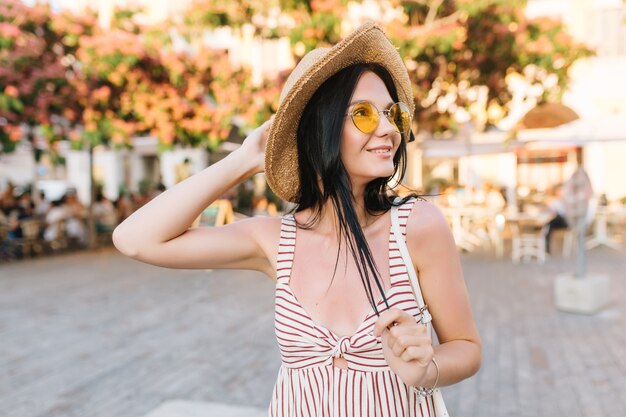 Geïnspireerd sierlijk meisje trendy bril en zomer hoed tijd buiten doorbrengen, genieten van warme dag