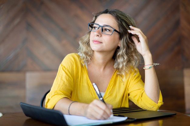 Geïnspireerde creatieve vrouw die ideeën neerschrijft