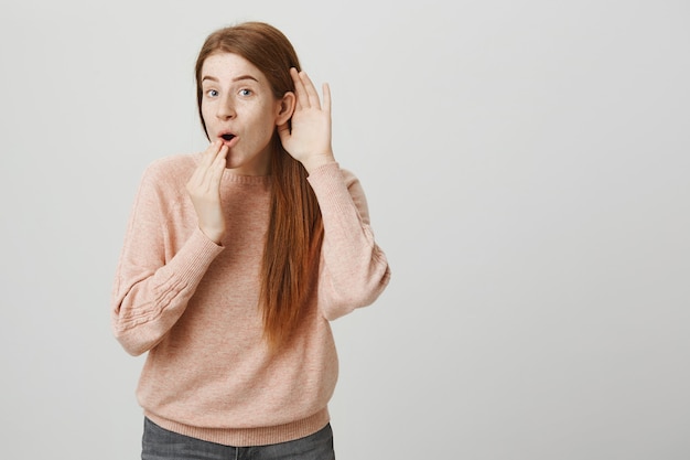 Geïntrigeerd roddelende roodharige meid die afluistert