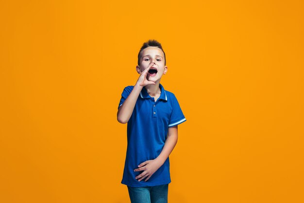 Geïsoleerd op oranje jonge casual tiener jongen schreeuwen