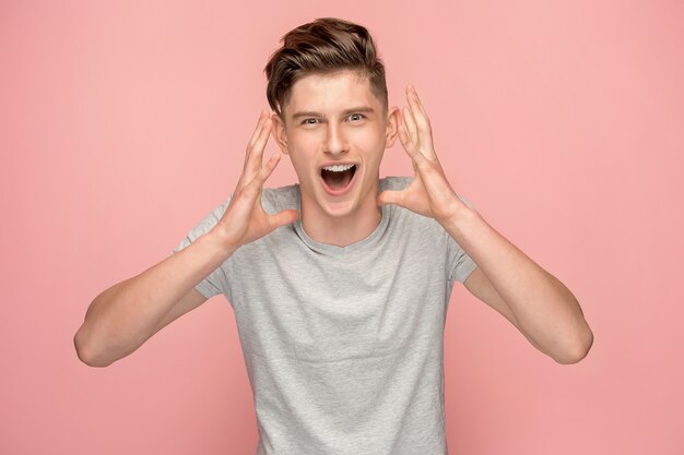 Geïsoleerd op roze casual jongeman schreeuwen in de studio