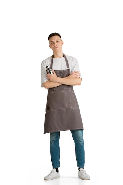 Geïsoleerd portret van een jonge mannelijke blanke barista in bruine schort