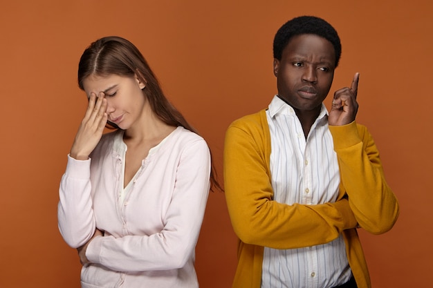 Geïsoleerde opname van een interraciaal team van twee collega's die samenwerken, proberen zich iets in gedachten te herinneren, de handen op hun gezicht vasthouden, een doordachte blik hebben, bezorgd over een probleem