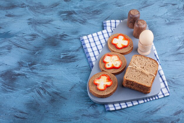 Gekookt ei en gesneden brood op een bord op theedoek, op de blauwe tafel.