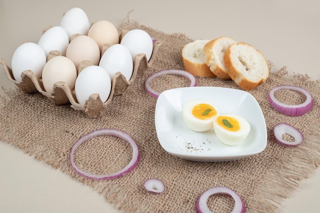 Gratis foto gekookt ei op witte plaat met vers wit brood op zak.