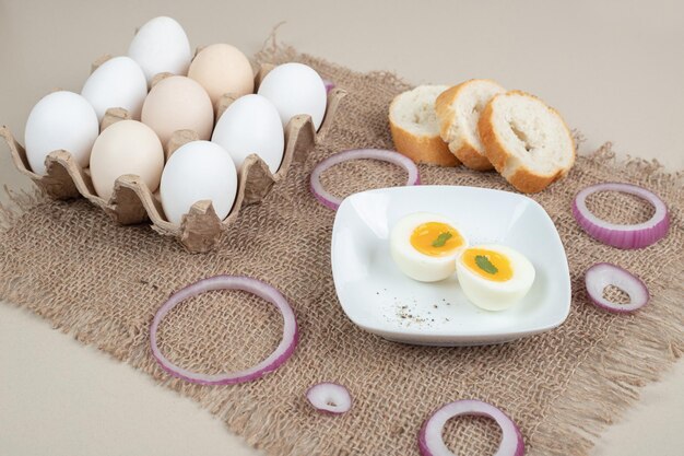 Gekookt ei op witte plaat met vers wit brood op zak.