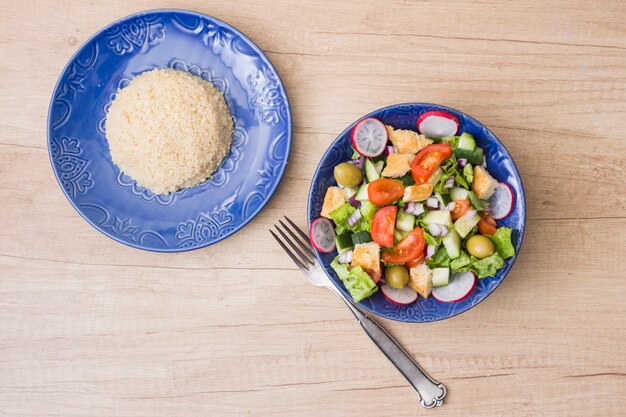 Gekookte rijst met plantaardige salade op houten tafel