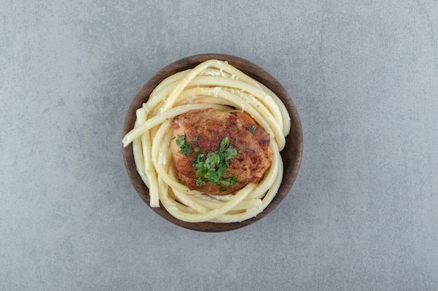 Gekookte spaghettideegwaren en geroosterde kip in houten kom.