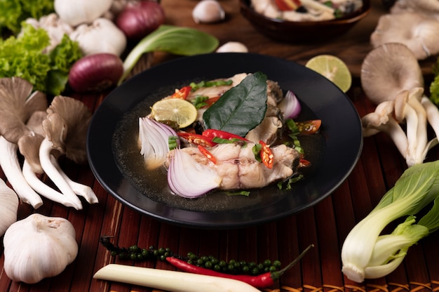 Gekookte visinfusie met tomaten, champignons, koriander, bosui en citroengras in een kom