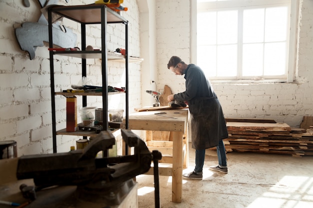 Gekwalificeerde zelfstandige timmerman die werkt met hout in timmerwerk-werkplaats interieur