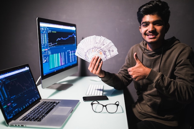 Geld verdienen online. Engelachtige rijke zakenman met nimbus op hoofd die dollarbankbiljetten richt, die aanmoedigen om op Internet te verdienen, zittend op laptop werkplaats. indoor studio shot geïsoleerd op een witte achtergrond