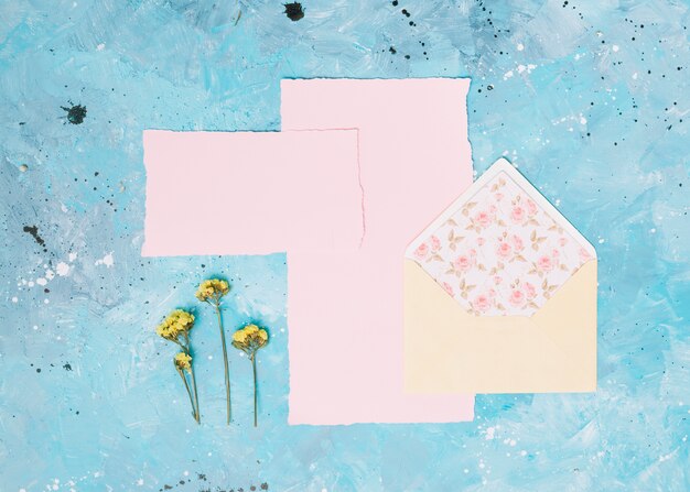 Gele bloemtakken met open envelop op blauwe lijst