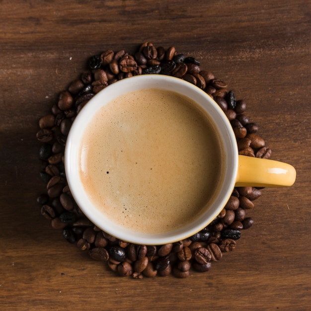 Gele kop met koffiebonen rond