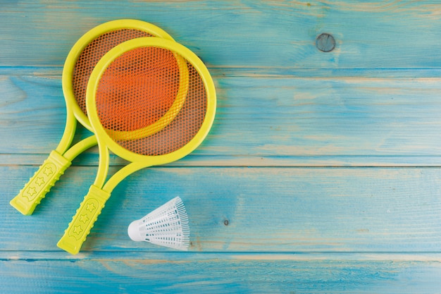 Gratis foto gele plastic tennisracket en shuttle op blauw geel turkoois bureau