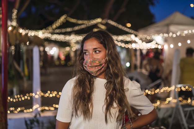 Gelooid Kaukasisch wijfje dat een bloemenmasker draagt bij een pretpark