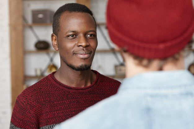 Gelukkig aantrekkelijke Afro-Amerikaanse jonge man lacht vrolijk tijdens een goed gesprek