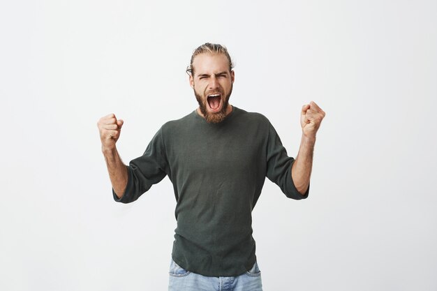 Gelukkig aantrekkelijke man met baard luid schreeuwen en expressief gebaren met handen