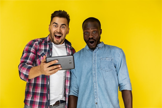 Gelukkig afgevraagd Europese en Afro-Amerikaanse man in informele shirts